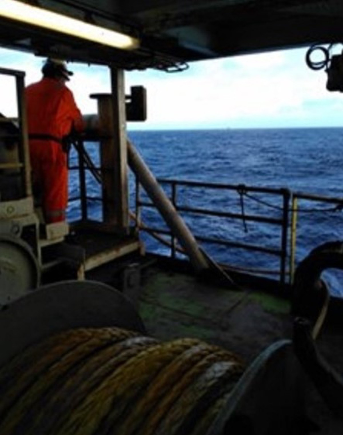 Injured person standing by railing on level below control panel with auxiliary winch in foreground