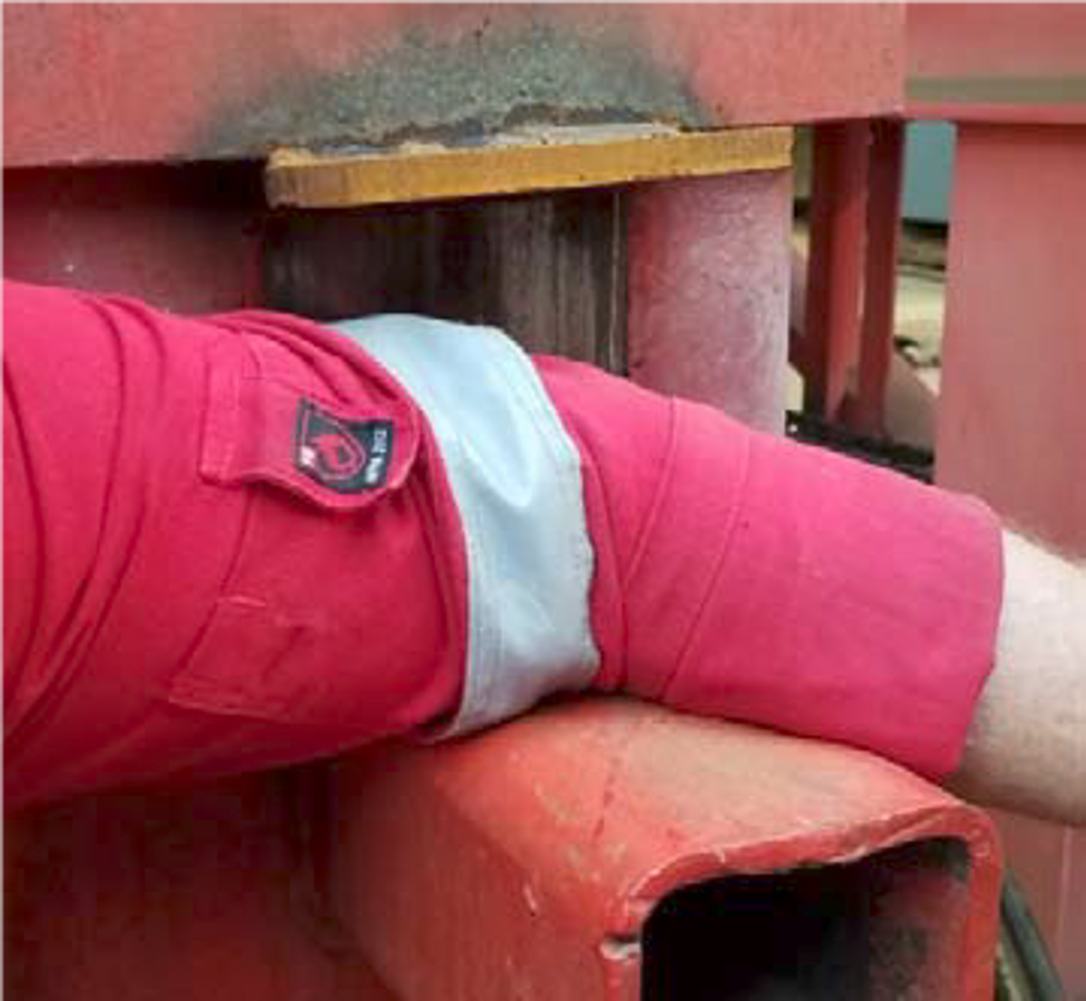 worker placed forearm on a hydraulically operated pipe stand