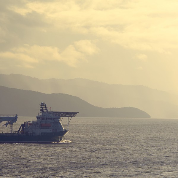 A photo of a vessel at sea at sunset