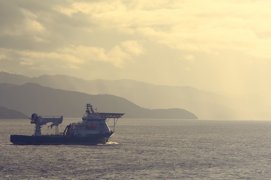 A photo of a vessel at sea at sunset